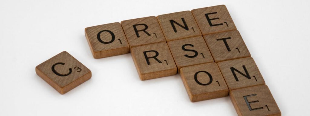 Wooden Scrabble tiles forming the word 'Cornerstone' on a white surface.