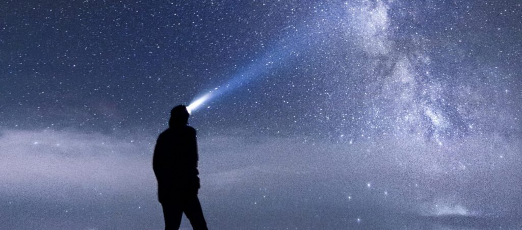 Silhouette of a person exploring the star-studded Milky Way sky at night in the mountains.