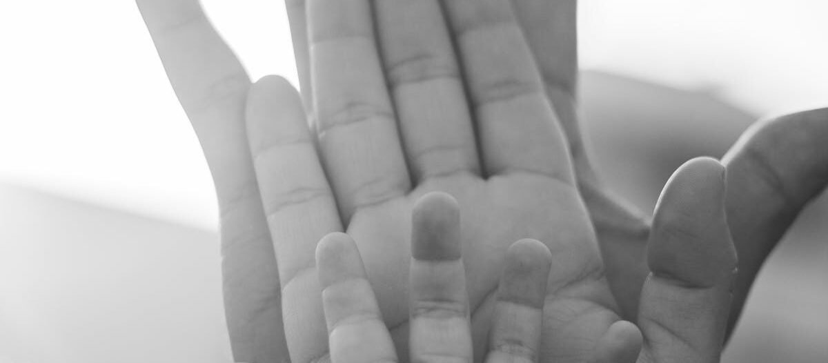 Black and white image of family hands symbolizing unity and generational ties.