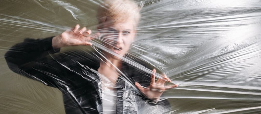 A woman pressed against a plastic sheet creating a sense of entrapment and surrealism.